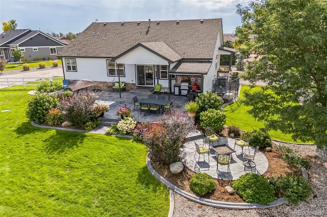 back of house featuring a yard, an outdoor fire pit, roof with shingles, and a patio area