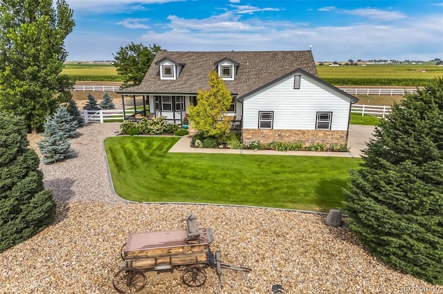 back of property with fence, covered porch, a shingled roof, stone siding, and a lawn