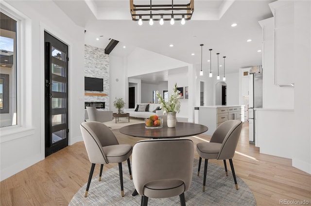 dining space featuring light wood-type flooring and a stone fireplace