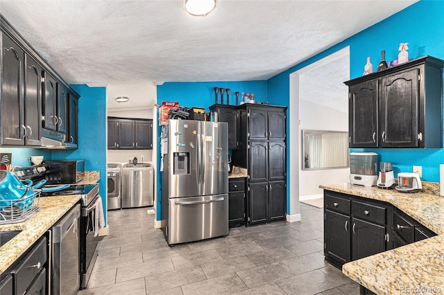 1390 W 78th Cir, Denver, CO 80221 - kitchen with appliances with stainless steel finishes, washer and dryer, a textured ceiling, light stone countertops, and range hood