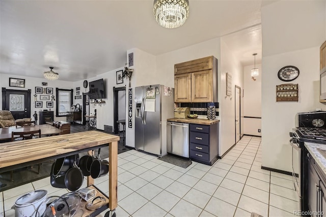 kitchen featuring a notable chandelier, backsplash, light tile patterned floors, and appliances with stainless steel finishes