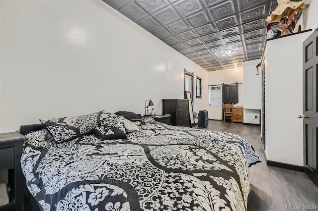 bedroom with hardwood / wood-style floors and a barn door