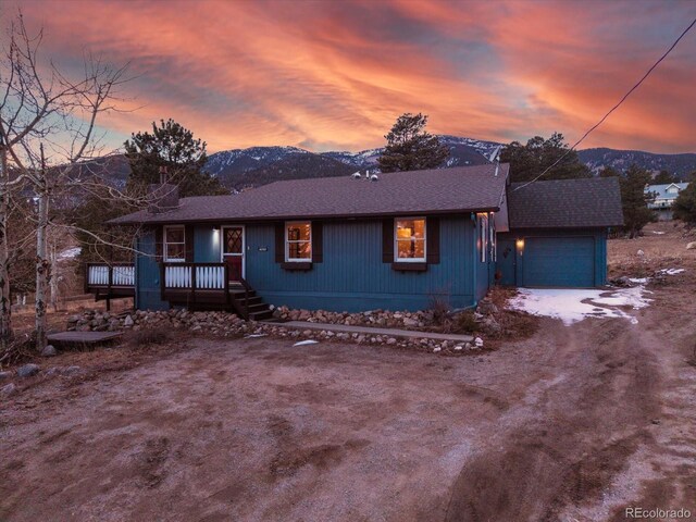 view of front of house with a deck with mountain view, an outdoor structure, and roof with shingles