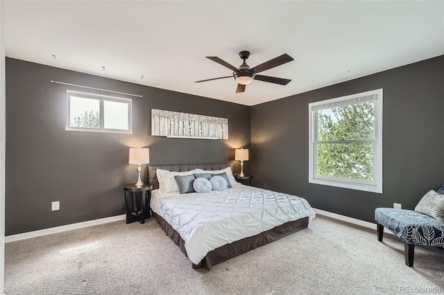 carpeted bedroom with multiple windows, baseboards, and a ceiling fan