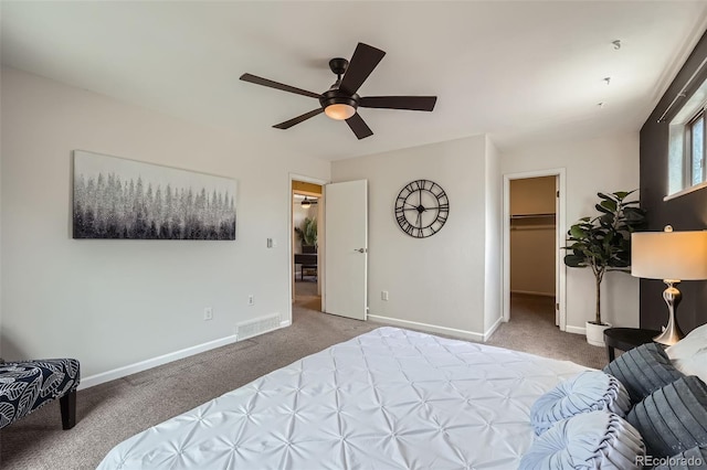 carpeted bedroom with baseboards, a spacious closet, and a ceiling fan