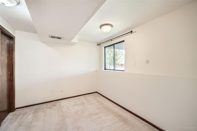 unfurnished room with light colored carpet, a textured ceiling, and baseboards