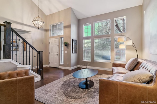 living room featuring dark wood-type flooring, high vaulted ceiling, and a chandelier