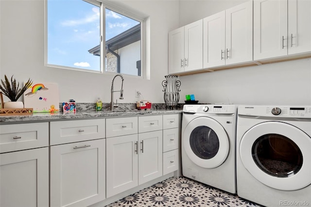 washroom featuring light tile patterned flooring, cabinets, washing machine and clothes dryer, and sink