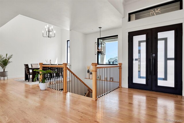 foyer entrance featuring french doors, wood-type flooring, and a chandelier