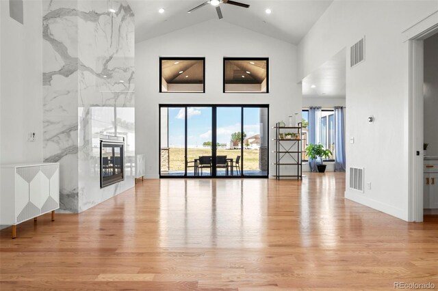 living room featuring ceiling fan, light wood-type flooring, and high vaulted ceiling