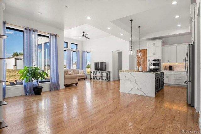 kitchen with appliances with stainless steel finishes, white cabinetry, ceiling fan, and light hardwood / wood-style floors