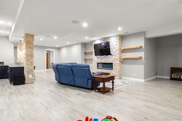 living room featuring light hardwood / wood-style flooring, sink, and a stone fireplace