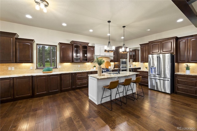 16104 Pole Pine Pt, Colorado Springs, CO 80908 - kitchen featuring stainless steel appliances, an island with sink, dark brown cabinetry, glass insert cabinets, and dark wood-type flooring