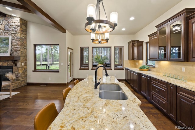 16104 Pole Pine Pt, Colorado Springs, CO 80908 - kitchen featuring a chandelier, light stone counters, dark brown cabinets, and glass insert cabinets