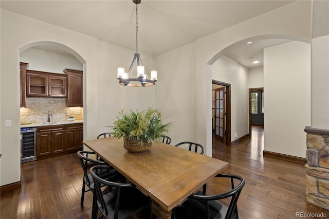 16104 Pole Pine Pt, Colorado Springs, CO 80908 - dining space with wine cooler, dark wood finished floors, a chandelier, recessed lighting, and arched walkways