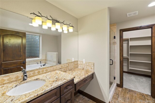 16104 Pole Pine Pt, Colorado Springs, CO 80908 - bathroom with a stall shower, vanity, a bath, wood finished floors, and a walk in closet