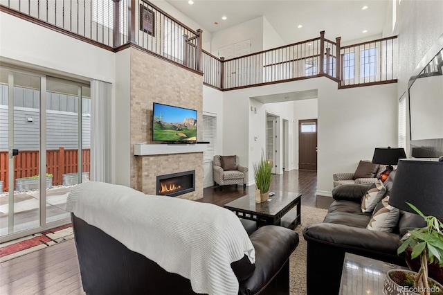 8464 E 55th Pl, Denver, CO 80238 - living area featuring wood finished floors, a towering ceiling, a glass covered fireplace, recessed lighting, and baseboards