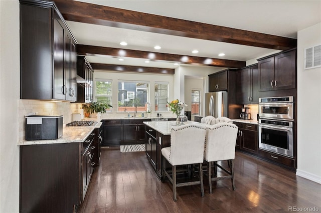 8464 E 55th Pl, Denver, CO 80238 - kitchen with stainless steel appliances, beamed ceiling, backsplash, light stone counters, and recessed lighting