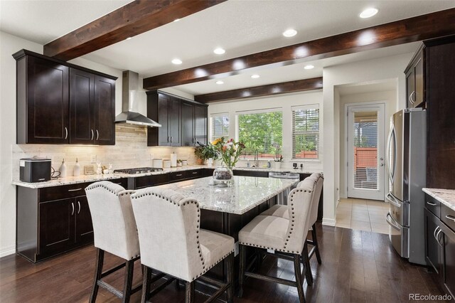 8464 E 55th Pl, Denver, CO 80238 - kitchen with wall chimney exhaust hood, appliances with stainless steel finishes, beamed ceiling, a kitchen bar, and backsplash