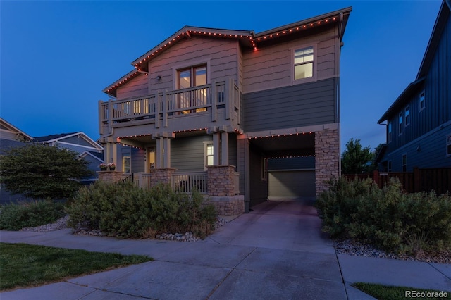 8464 E 55th Pl, Denver, CO 80238 - view of front of home featuring stone siding, a balcony, driveway, a garage, and a porch