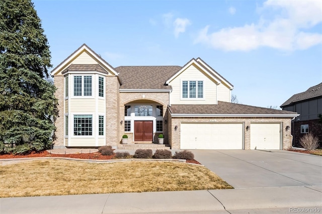 traditional-style house with a front yard, brick siding, roof with shingles, and driveway