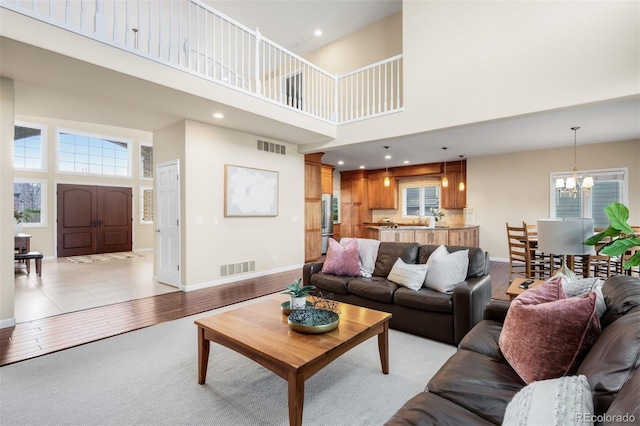 living area with a notable chandelier, baseboards, visible vents, and light wood-type flooring