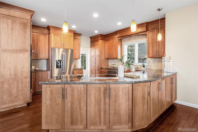 kitchen with a peninsula, dark stone countertops, dark wood-style floors, and high end fridge