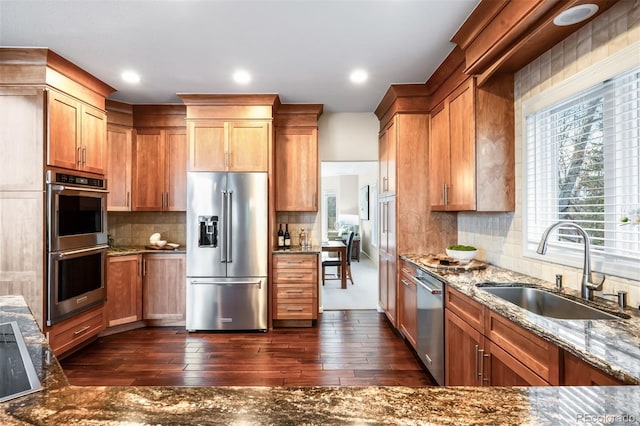 kitchen featuring tasteful backsplash, a sink, stone countertops, stainless steel appliances, and dark wood-style flooring