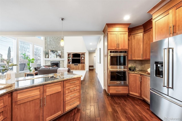 kitchen featuring light stone counters, stainless steel appliances, dark wood-type flooring, and open floor plan