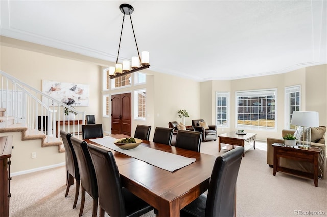 dining room featuring stairway, light carpet, baseboards, and a chandelier