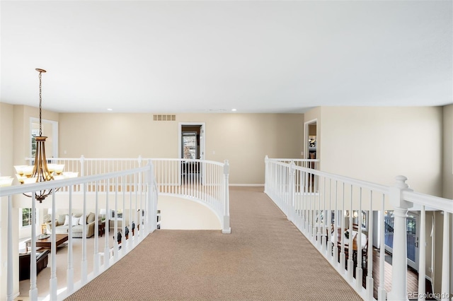 hallway featuring visible vents, an upstairs landing, a notable chandelier, recessed lighting, and carpet flooring