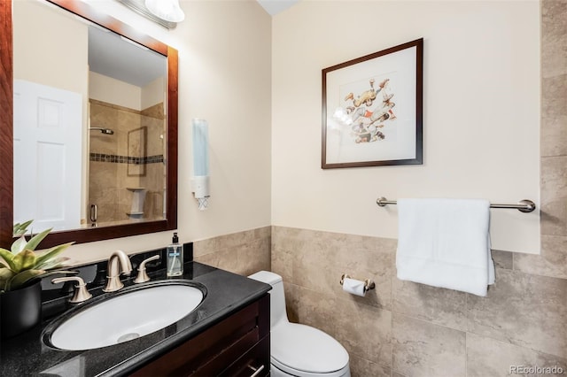 full bathroom with a shower stall, tile walls, vanity, and toilet