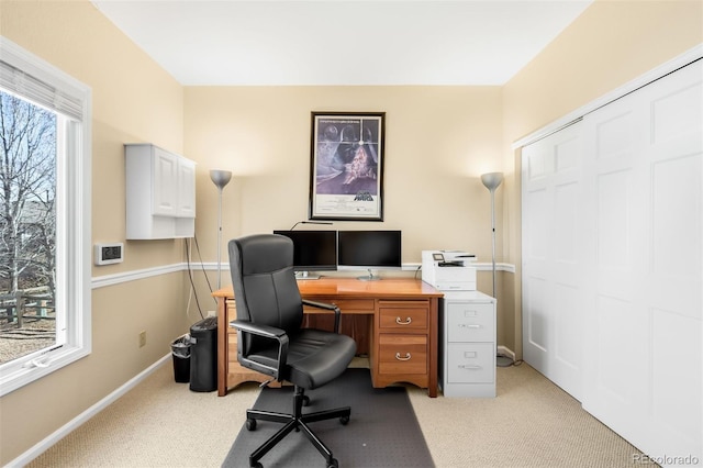 office area featuring a wealth of natural light, baseboards, and light carpet