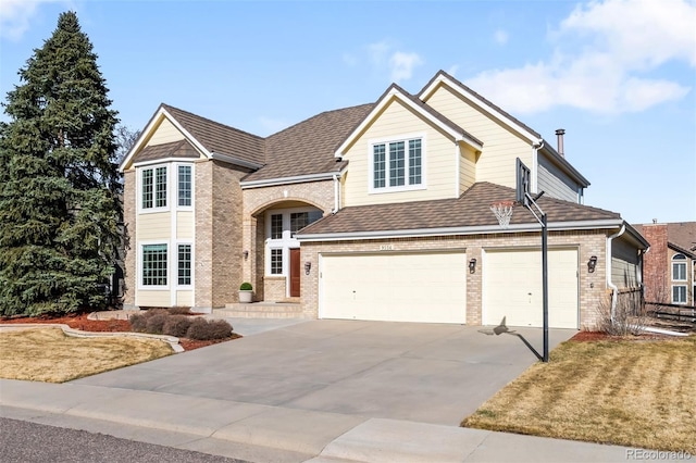 traditional-style house with brick siding, an attached garage, concrete driveway, and roof with shingles