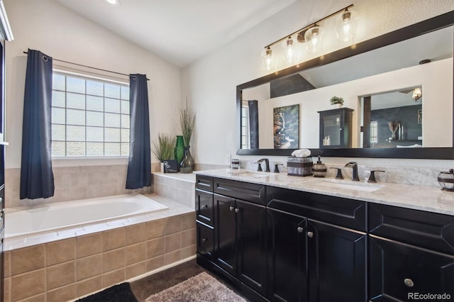 bathroom featuring vanity, tiled bath, and vaulted ceiling