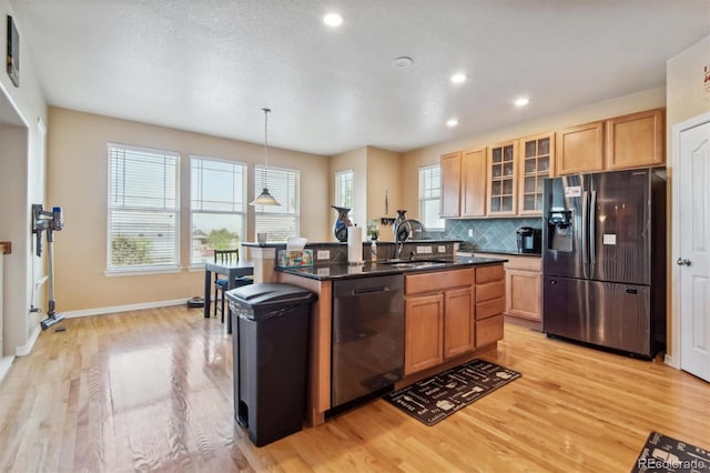 kitchen featuring pendant lighting, a center island with sink, sink, light hardwood / wood-style flooring, and appliances with stainless steel finishes