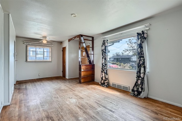 empty room featuring baseboards, a ceiling fan, visible vents, and wood finished floors