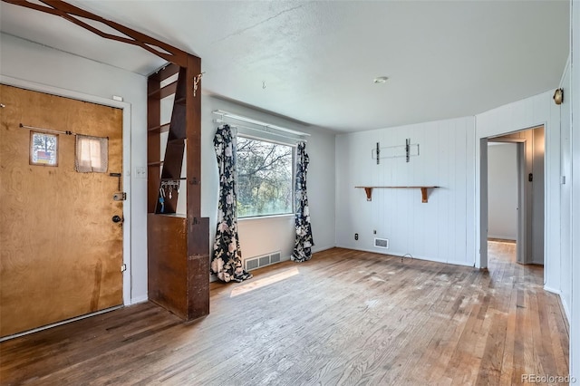 unfurnished room with visible vents, wood finished floors, baseboards, and a healthy amount of sunlight