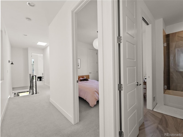 corridor featuring carpet flooring, baseboards, and an upstairs landing
