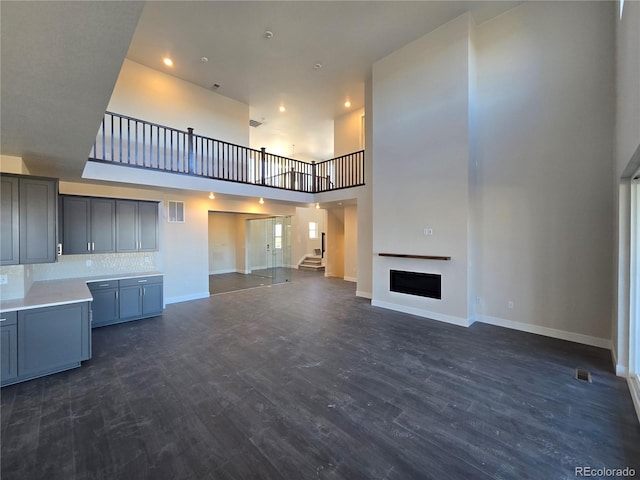 unfurnished living room with dark hardwood / wood-style flooring and a high ceiling