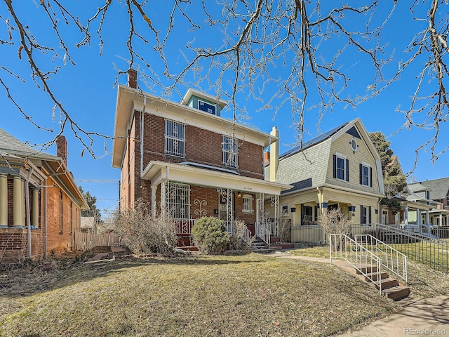 american foursquare style home with covered porch, fence, a front lawn, and brick siding