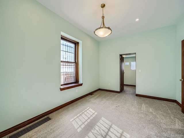 unfurnished room featuring visible vents, light carpet, and baseboards