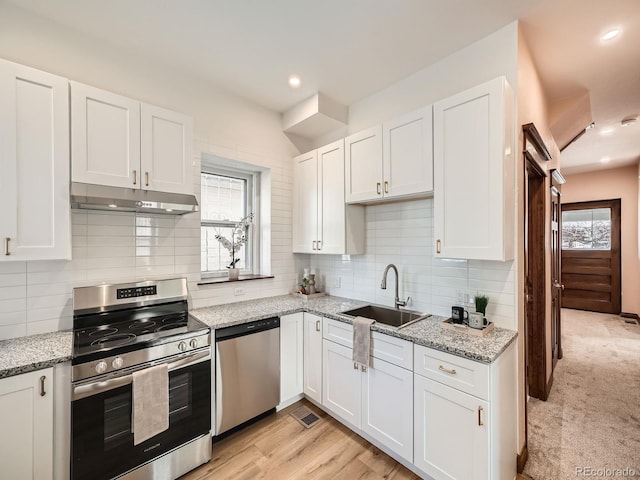 kitchen featuring under cabinet range hood, appliances with stainless steel finishes, white cabinets, and a sink