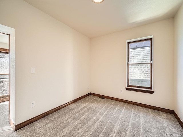 carpeted spare room featuring baseboards