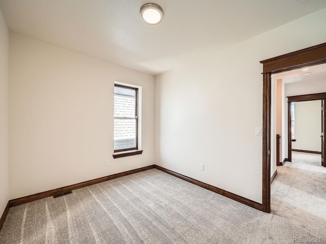 carpeted spare room featuring visible vents and baseboards