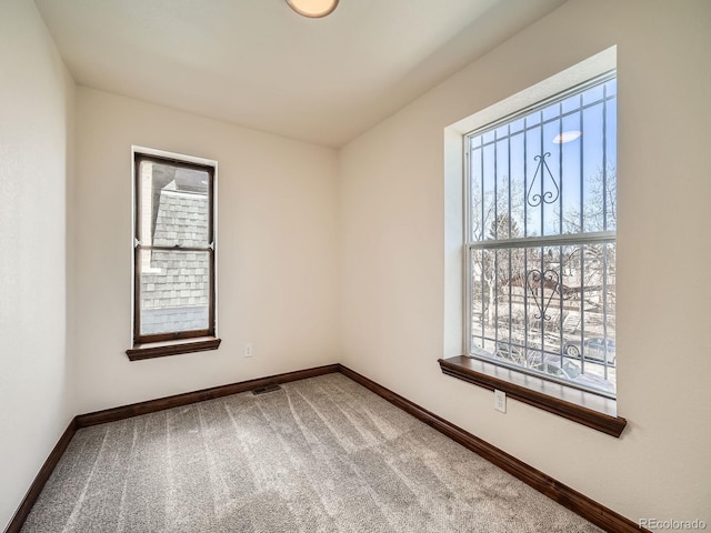 carpeted spare room featuring visible vents and baseboards