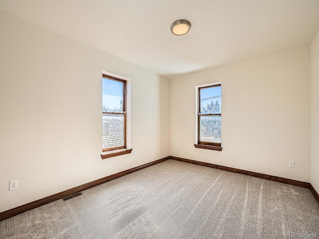 empty room featuring light colored carpet, visible vents, and baseboards