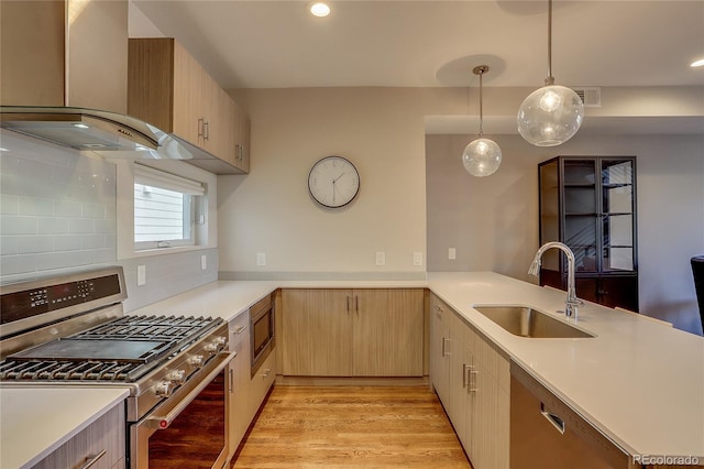 kitchen with sink, appliances with stainless steel finishes, wall chimney range hood, and light brown cabinets