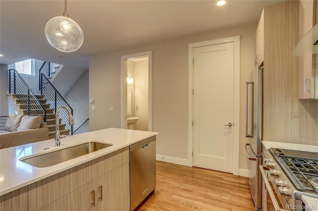 kitchen with light brown cabinetry, sink, decorative light fixtures, light hardwood / wood-style flooring, and high end appliances