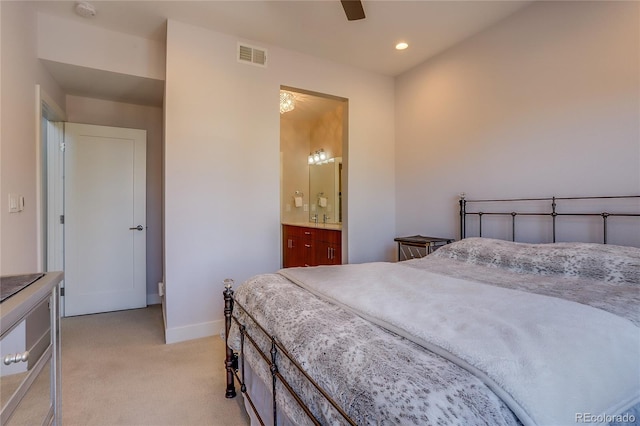 bedroom featuring ensuite bathroom, light colored carpet, and ceiling fan